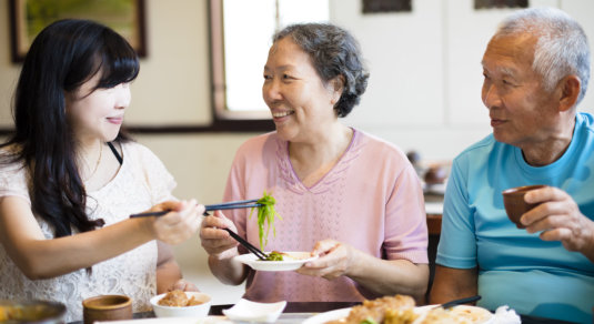 elderly couple eating with their caregiver
