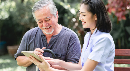 caregiver taking notes from elder man