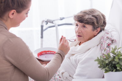 caregiver feeding the senior woman at the bedroom