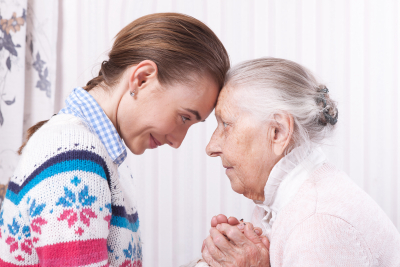 senior woman and caregiver holding hands